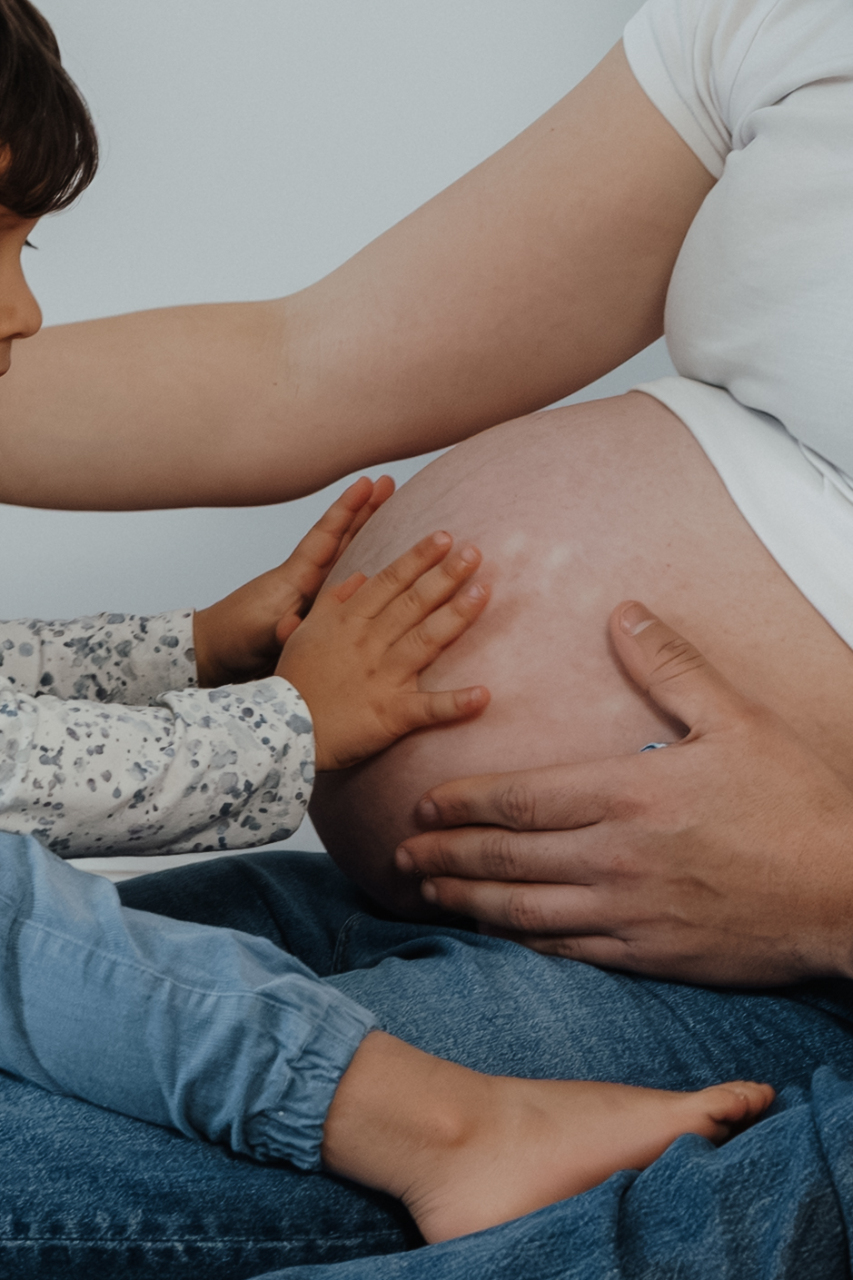 Zarte Berührung des Babybauchs, leise und gefühlvoll fotografiert.