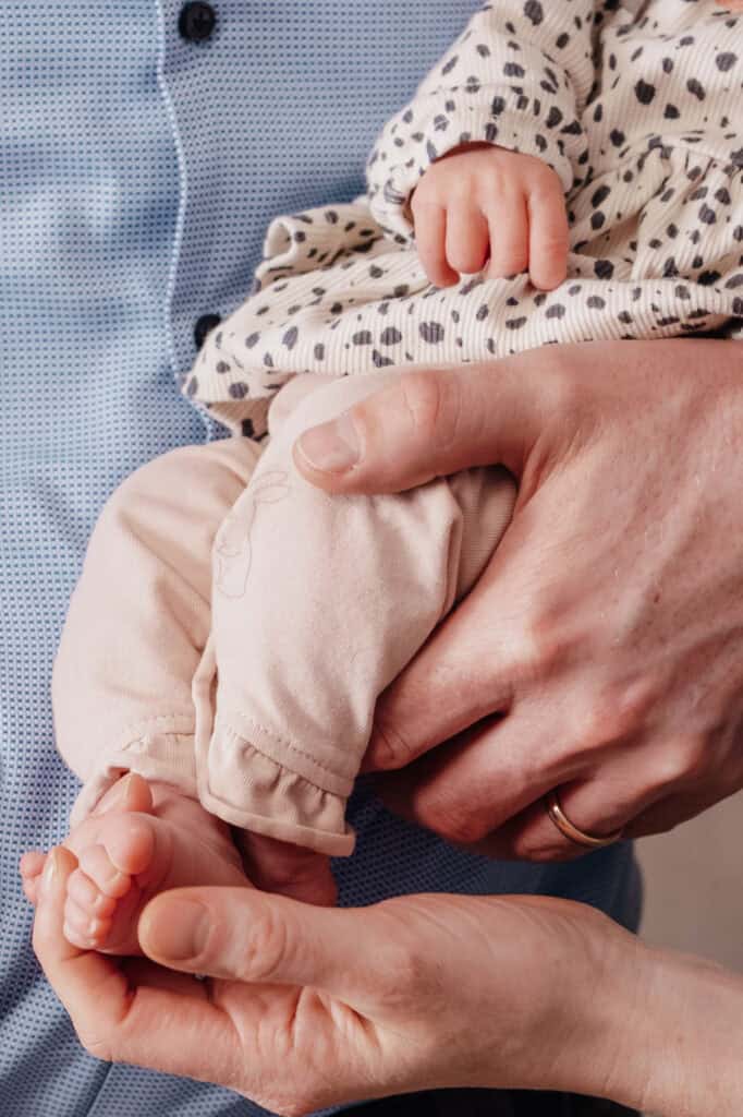 Natürliche Familienfotografie in Hamburg – liebevolle Detailaufnahme von Elternhänden und Kinderfuß