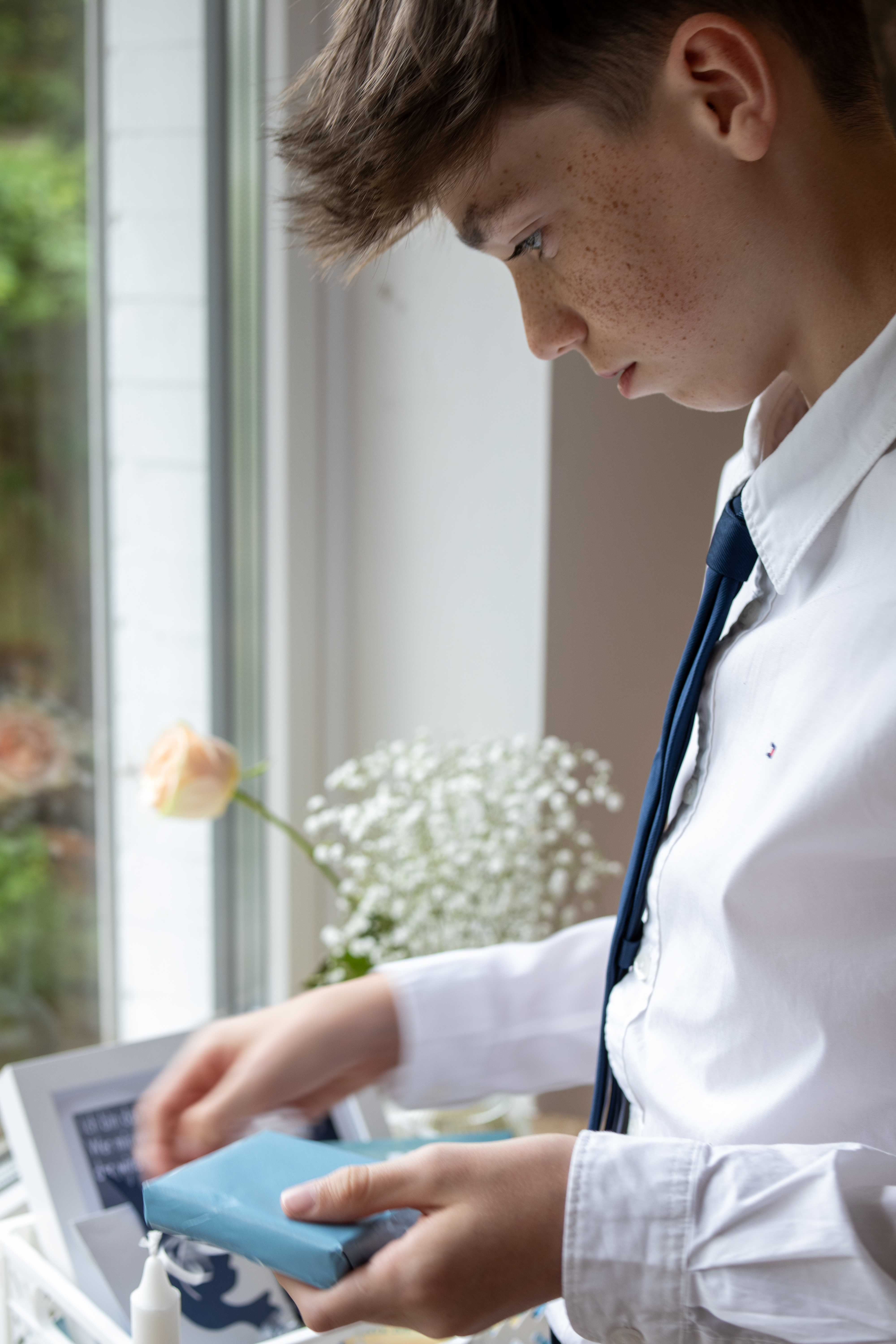 Konfirmand beim Auspacken von Geschenken im Kreis der Familie – Konfirmationsfotografie